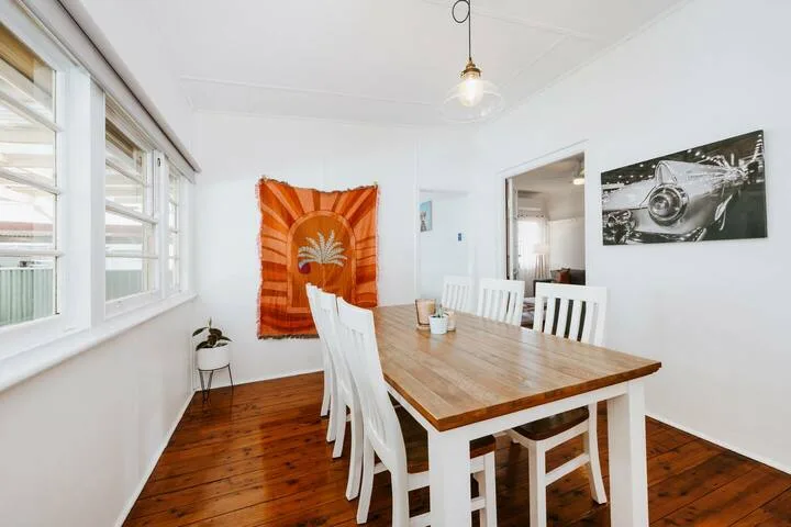 Un comedor luminoso con una mesa de madera junto a grandes ventanas.