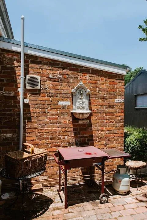Un patio de ladrillo con una mesa y una fuente en la pared.