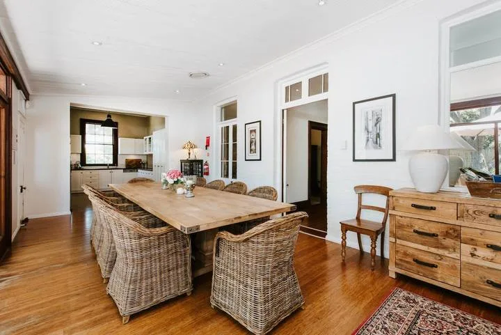 Un comedor con una mesa larga de madera y asientos tejidos.