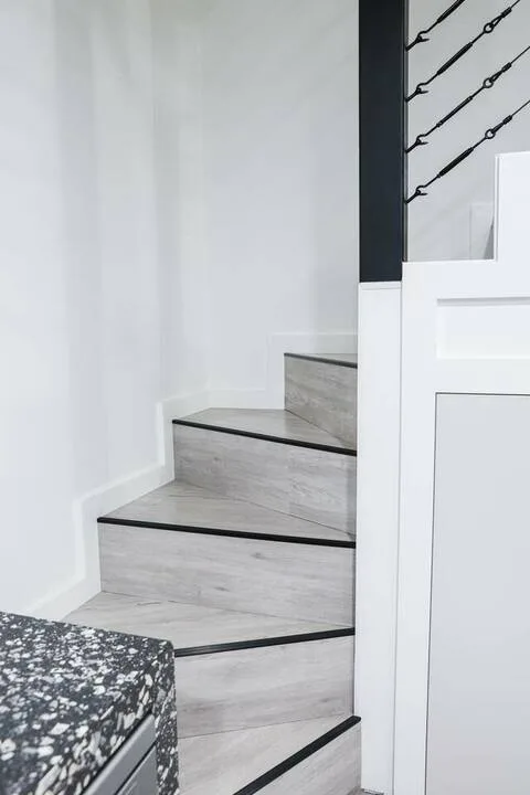 Escalera interior con peldaños claros y bordes oscuros.
