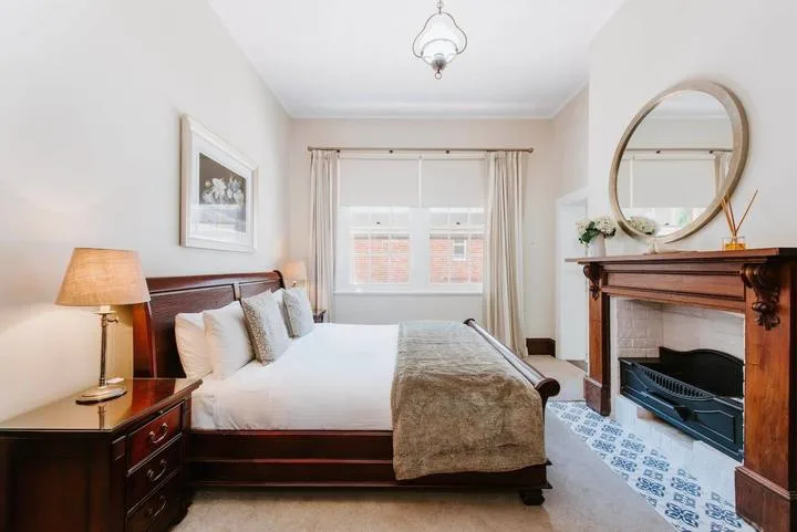 Un dormitorio con una cama bien tendida y una chimenea.
