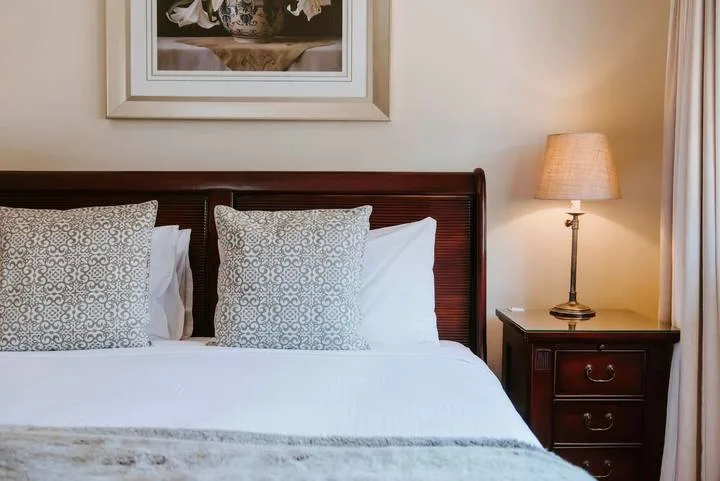 Un dormitorio con una cama bien arreglada y una lámpara sobre la mesita de noche.
