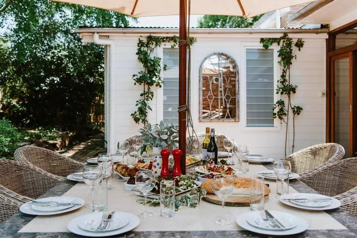 Una mesa al aire libre está preparada con comida bajo una sombrilla de patio.