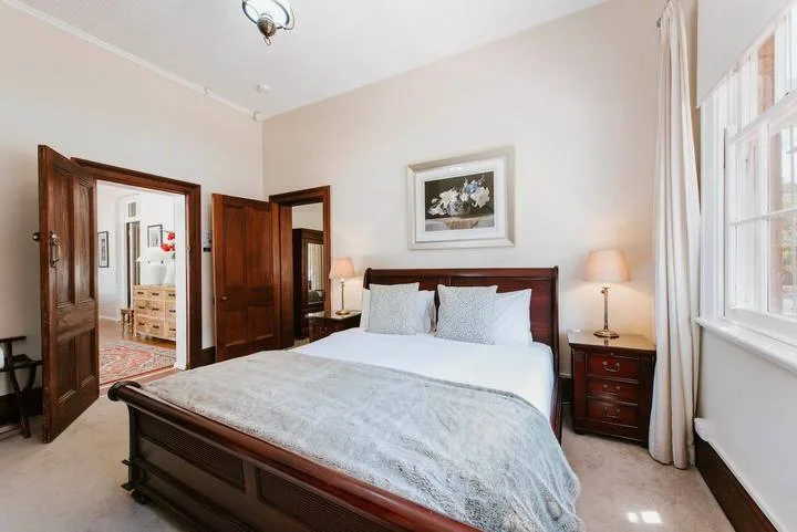 Un dormitorio con una cama de madera, mesitas de noche y una ventana grande.