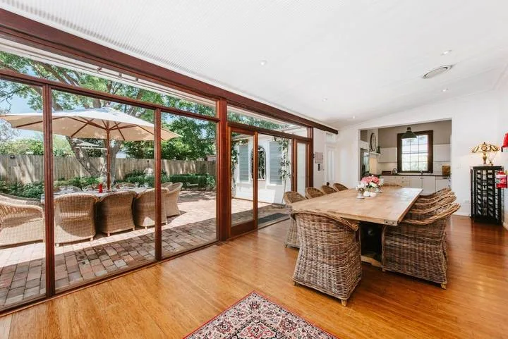 Comedor con una larga mesa de madera y grandes puertas de vidrio que dan a un patio.