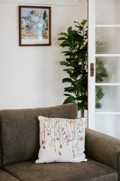 Una zona de estar con un cojín estampado y una planta frondosa.