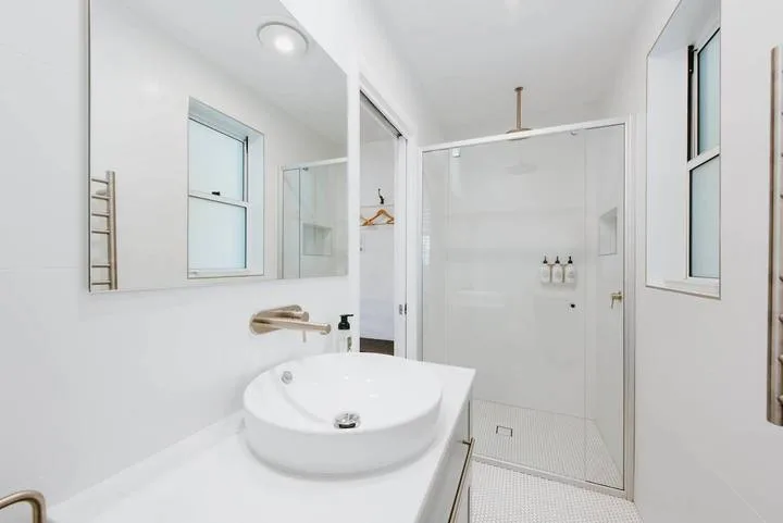 Un baño luminoso con lavabo, armario con espejo y ducha.