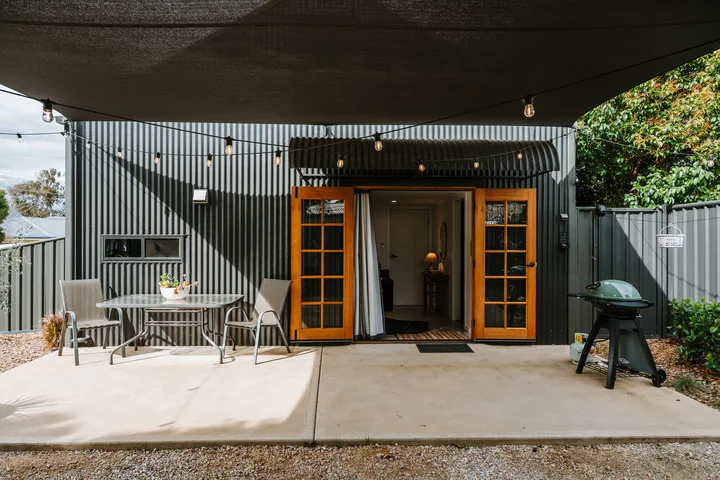 Un patio exterior cubierto con una mesa, asientos y una puerta abierta.