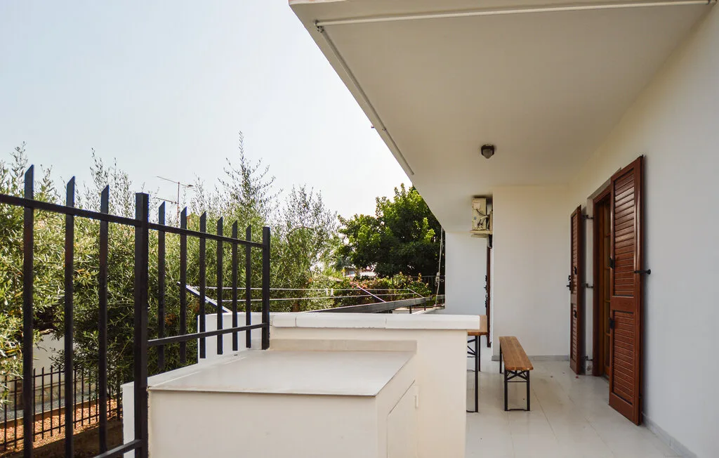 Una terraza exterior cubierta con suelo de baldosas y una barandilla negra de metal.