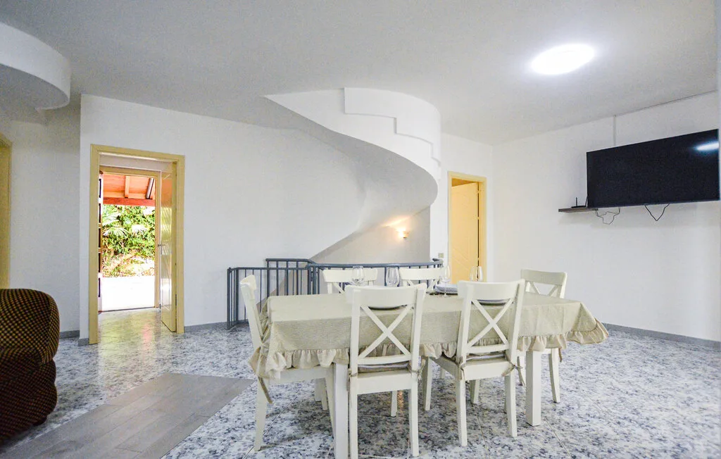 Un comedor con una mesa larga y sillas bajo una escalera curva.