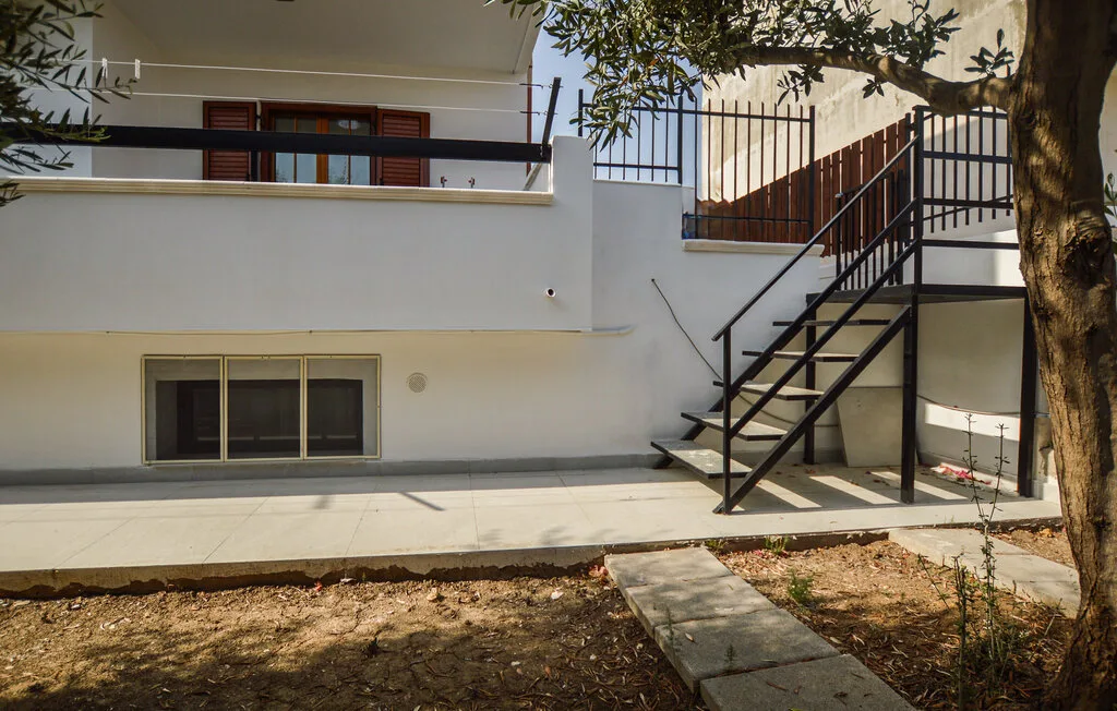Un patio exterior con un sendero pavimentado y escaleras metálicas junto a un edificio blanco.