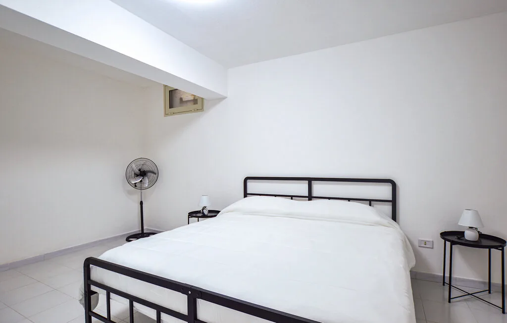 Un dormitorio con una cama y un ventilador de pie.