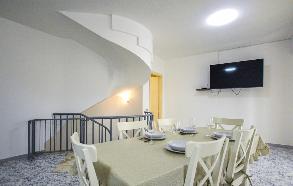 Comedor con una mesa puesta debajo de un televisor montado en la pared.