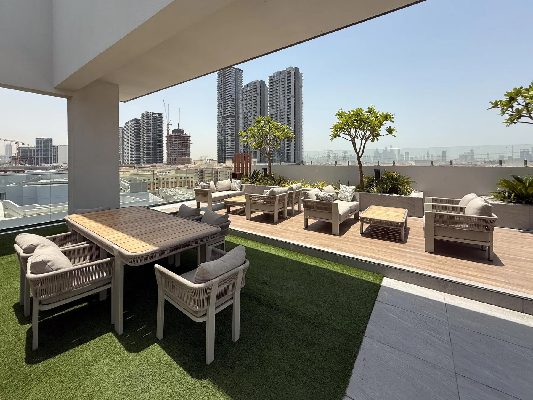 Una terraza en la azotea tiene asientos al aire libre, mesas bajas y una franja de césped artificial.