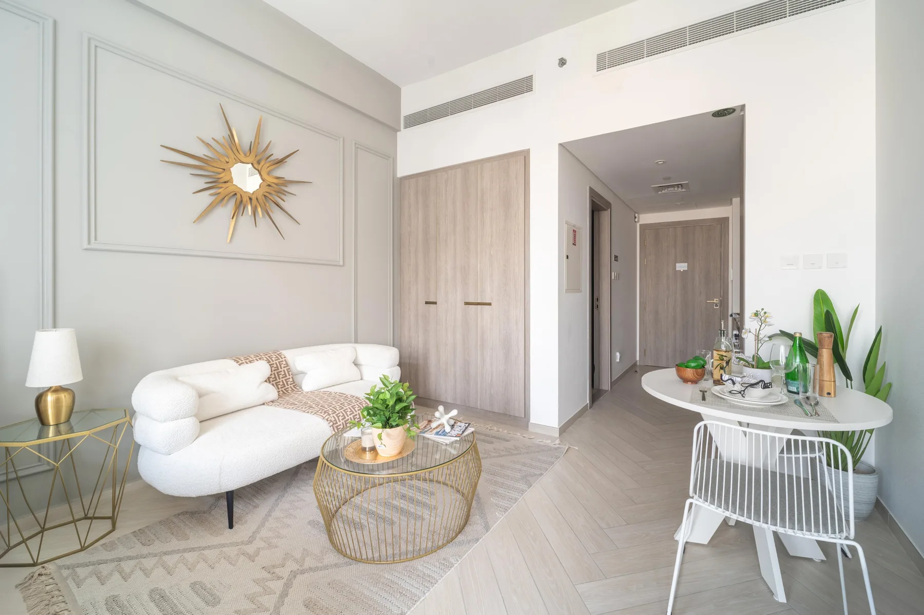 Una sala luminosa con un sofá blanco y un pequeño comedor.