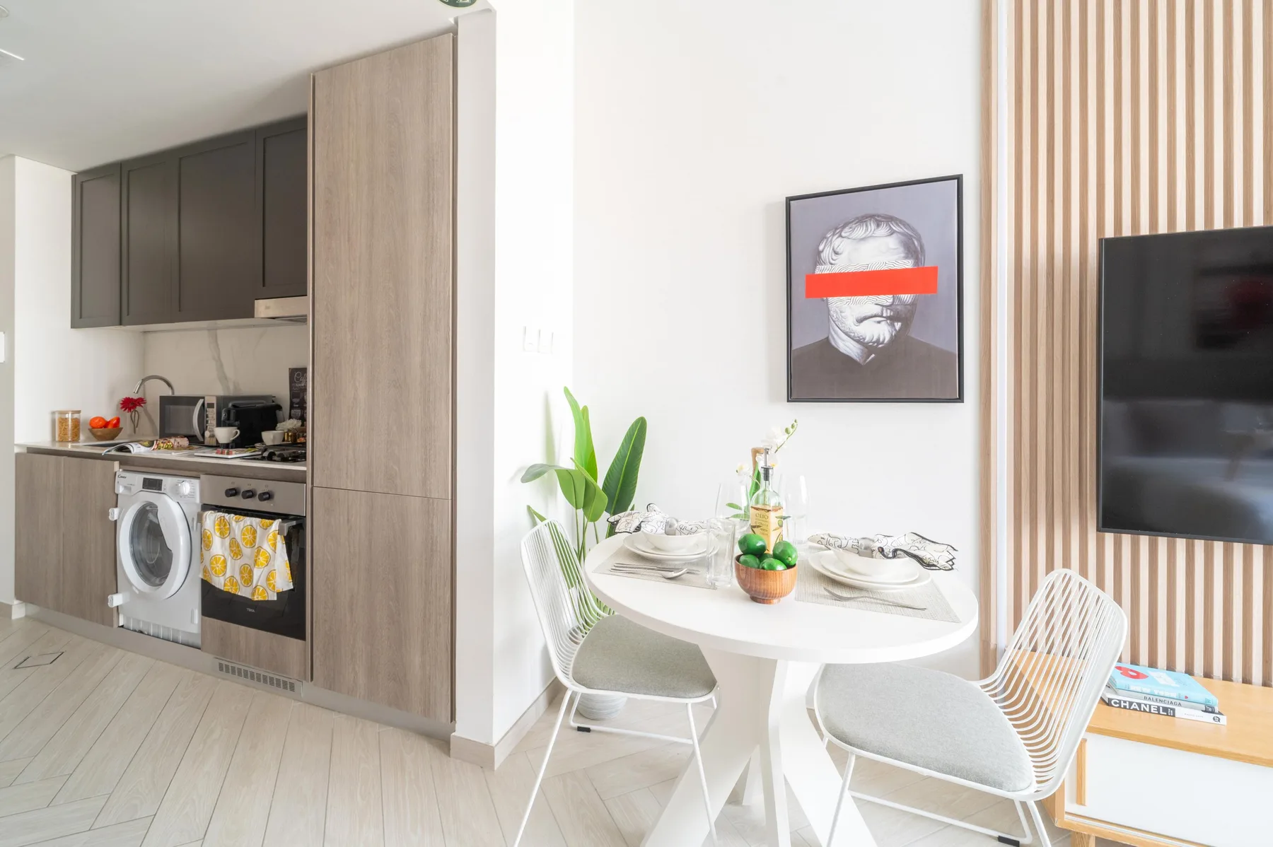 Una cocina y comedor luminosos con una mesa redonda y un televisor en la pared.