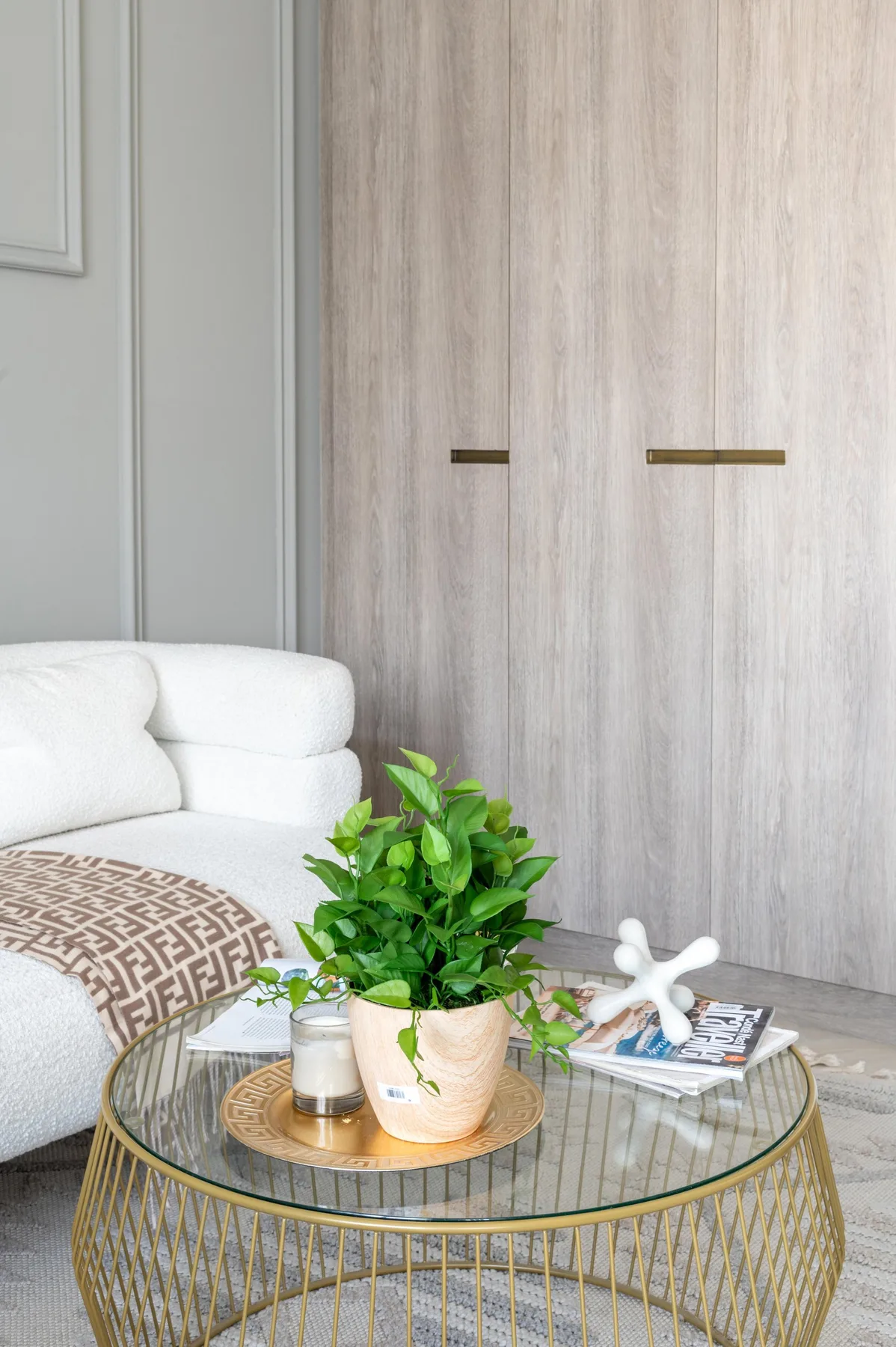 Una sala luminosa con asientos blancos y una mesa de centro de vidrio con una planta.