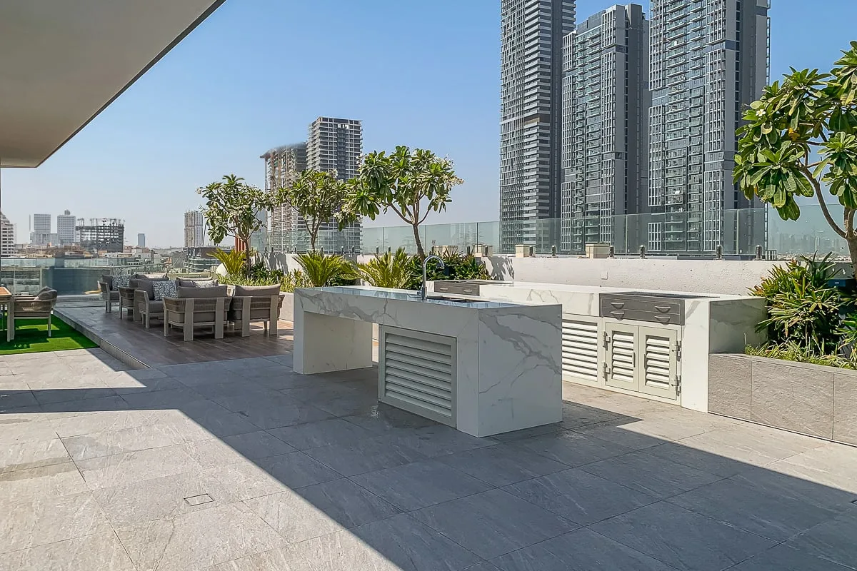Una terraza en la azotea con asientos al aire libre, jardineras y edificios altos cercanos.