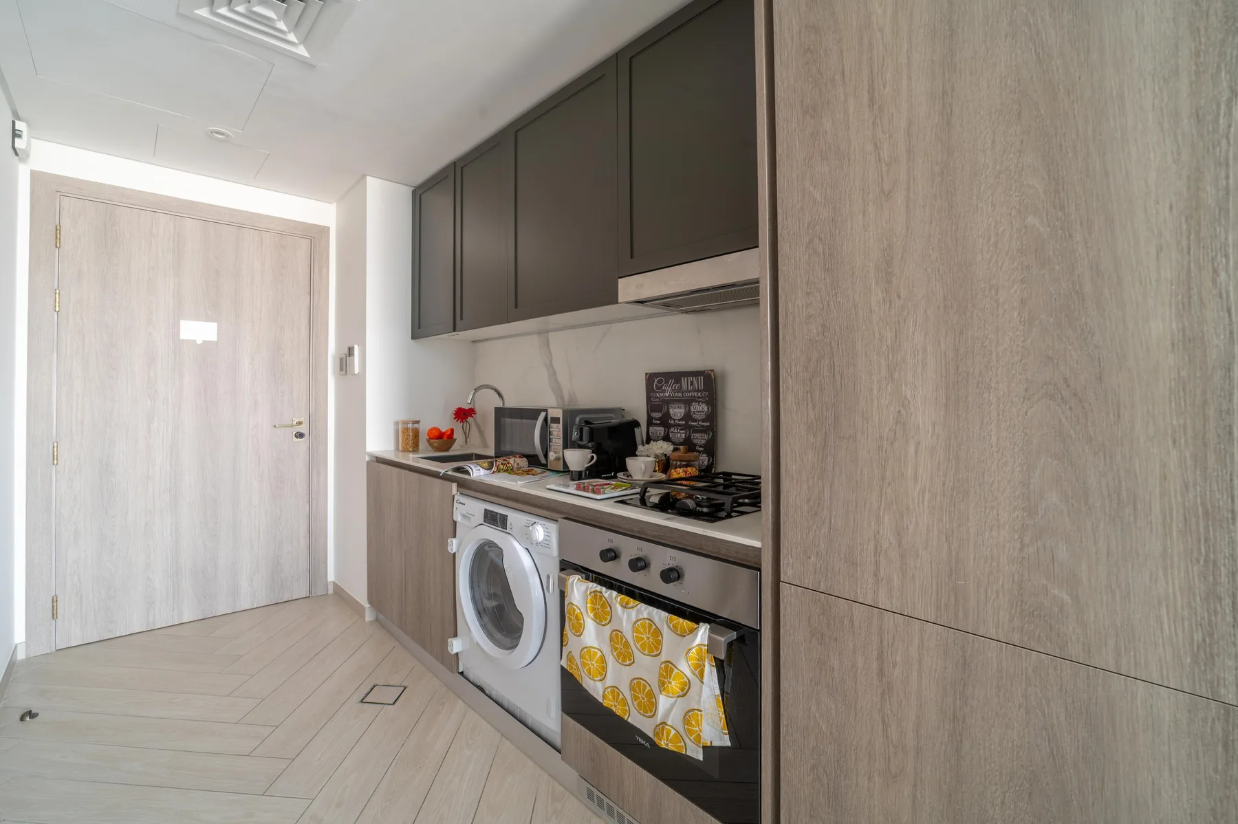 Una cocina compacta con armarios oscuros, una lavadora y un horno.