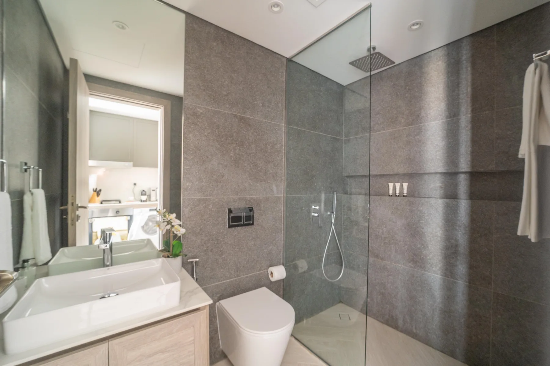 Un baño moderno con lavabo, inodoro y ducha con paneles de vidrio.