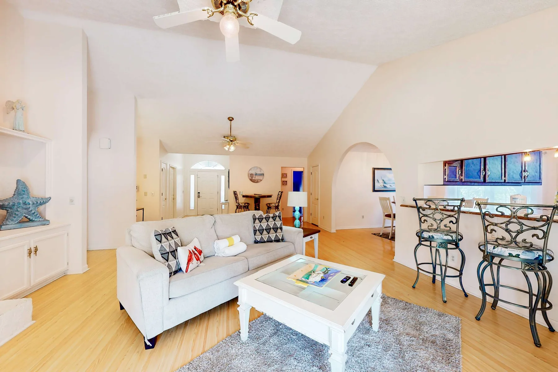 A bright living room with a white sofa and a dining table.