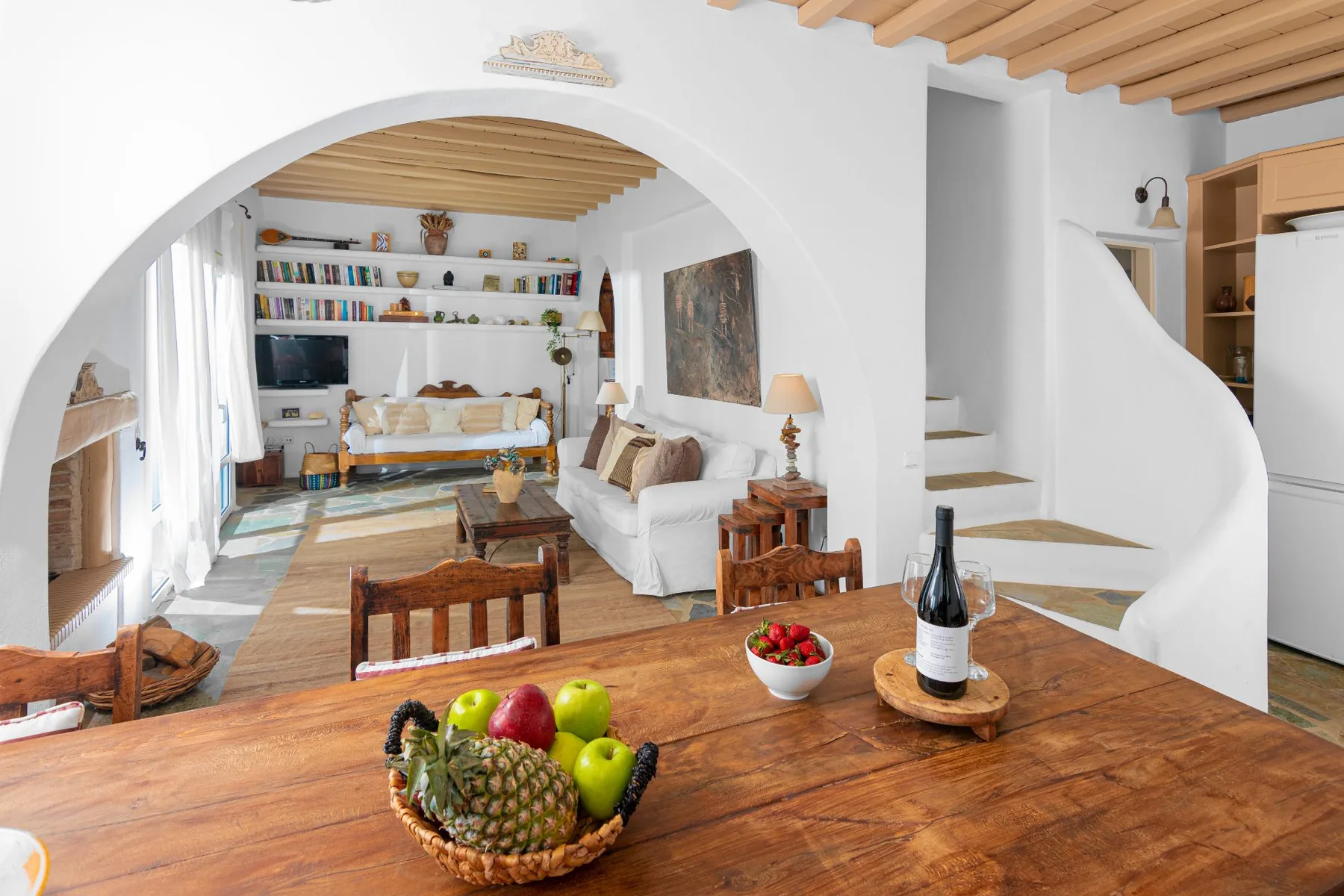 A living room with a wooden dining table and seating beneath an arched opening.