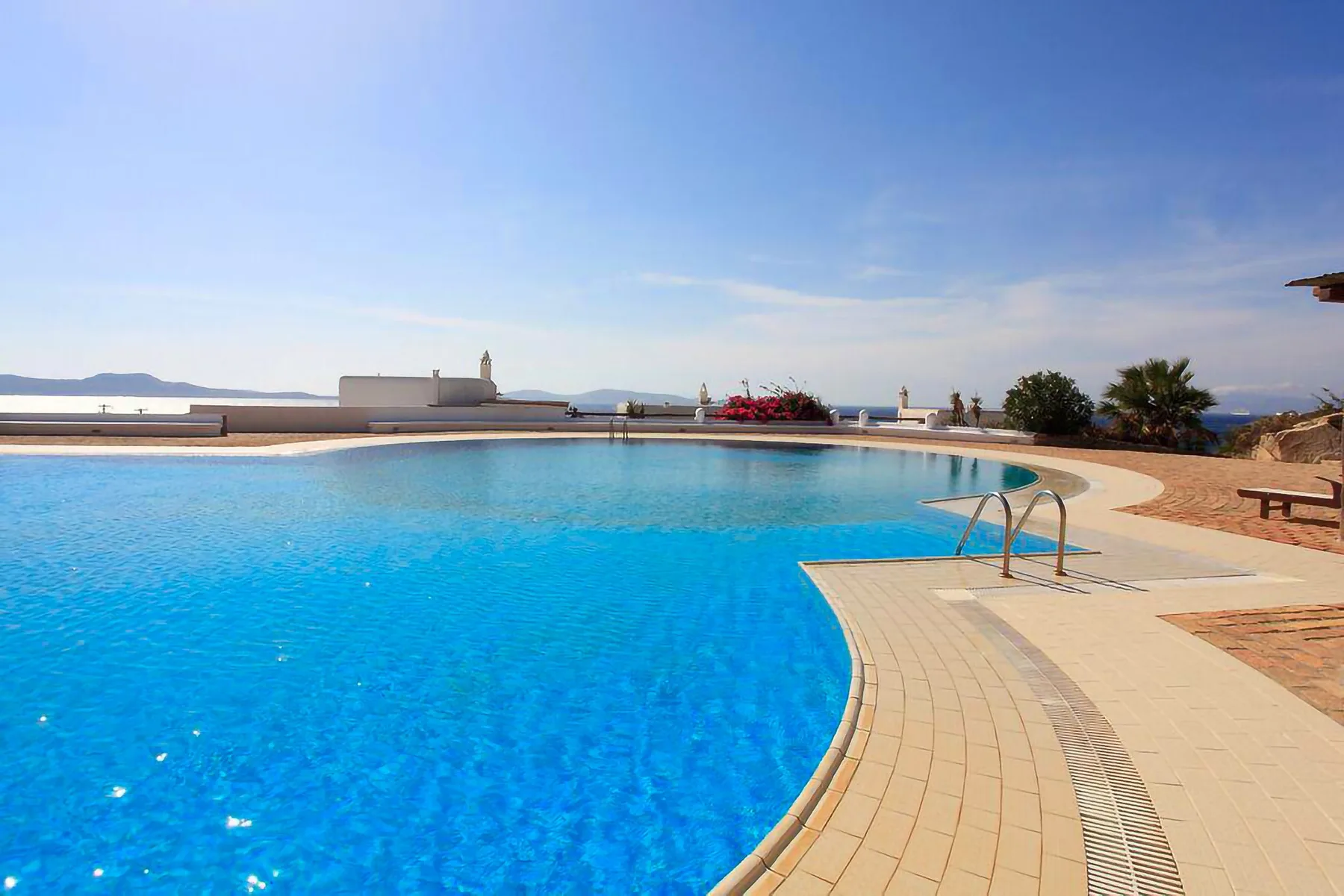 A swimming pool with a curved tiled deck and distant water views.