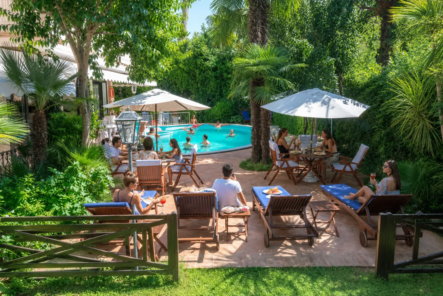 Piscina al aire libre junto a un patio a la sombra y un seto.