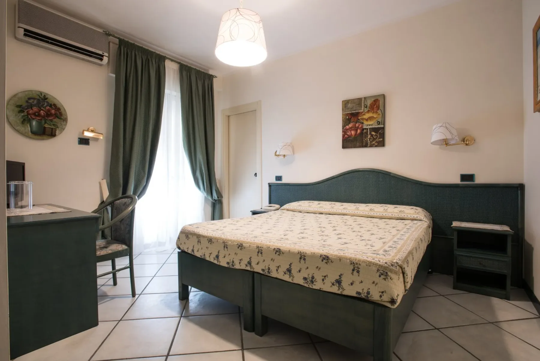 Habitación con una cama doble, cortinas verdes y un escritorio.