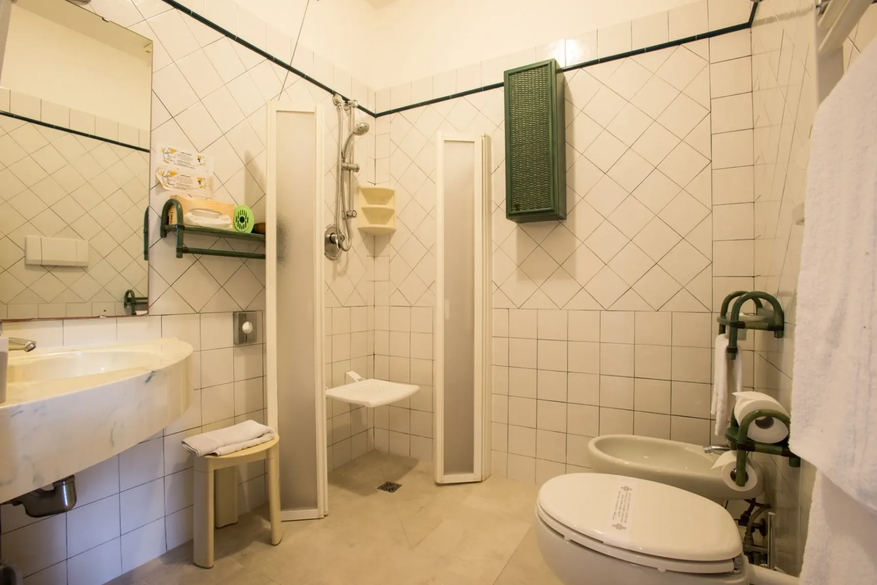 Baño accesible con silla de ducha y barras de apoyo.