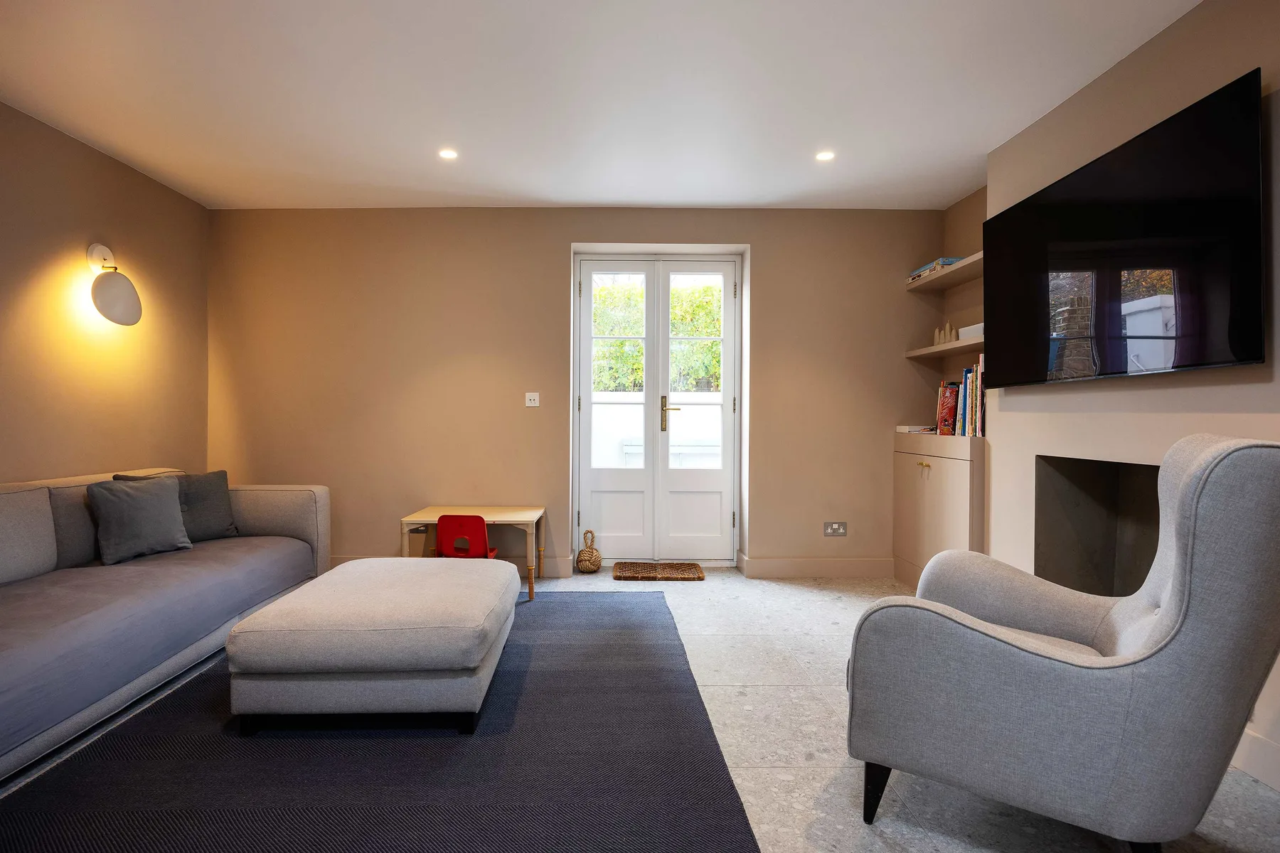 A living room with seating, a television, and white French doors.