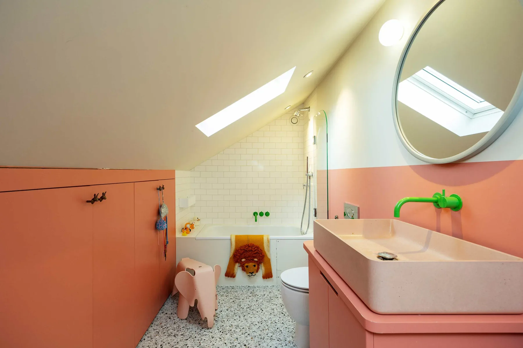 A colorful bathroom with a sink, toilet, and shower beneath a sloped ceiling.