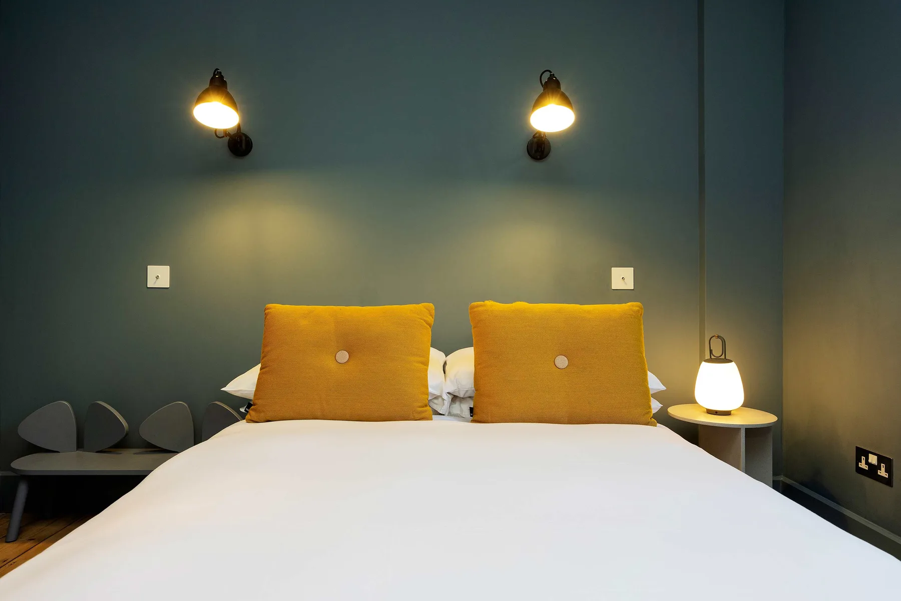 A bedroom with a neatly made bed and two mustard-colored pillows.