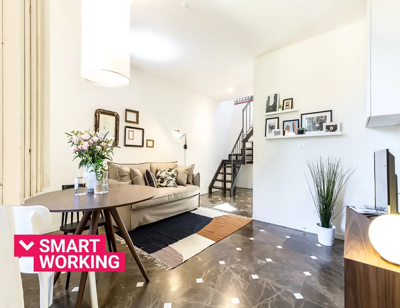 A bright living room with a sofa, dining table, and staircase.
