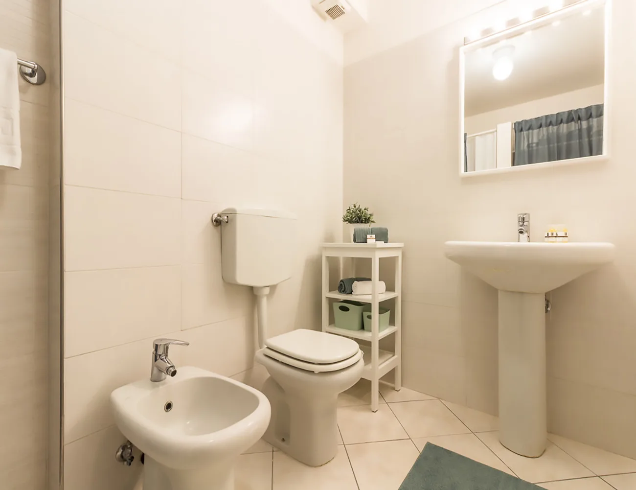Un baño luminoso con azulejos, inodoro, bidé y lavabo.