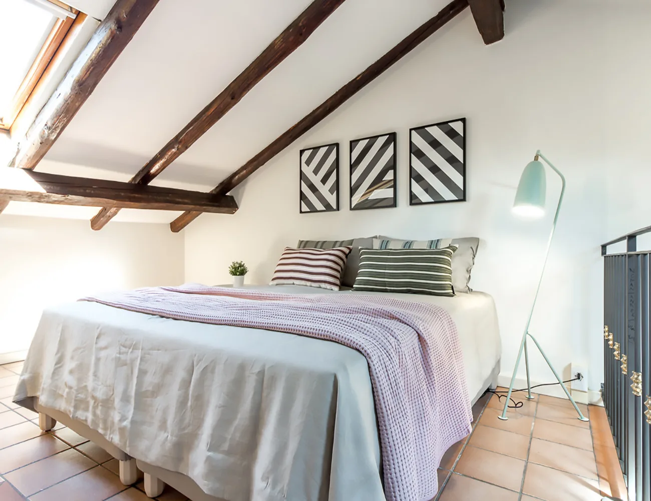 Un dormitorio con una cama bajo vigas oscuras expuestas en el techo.