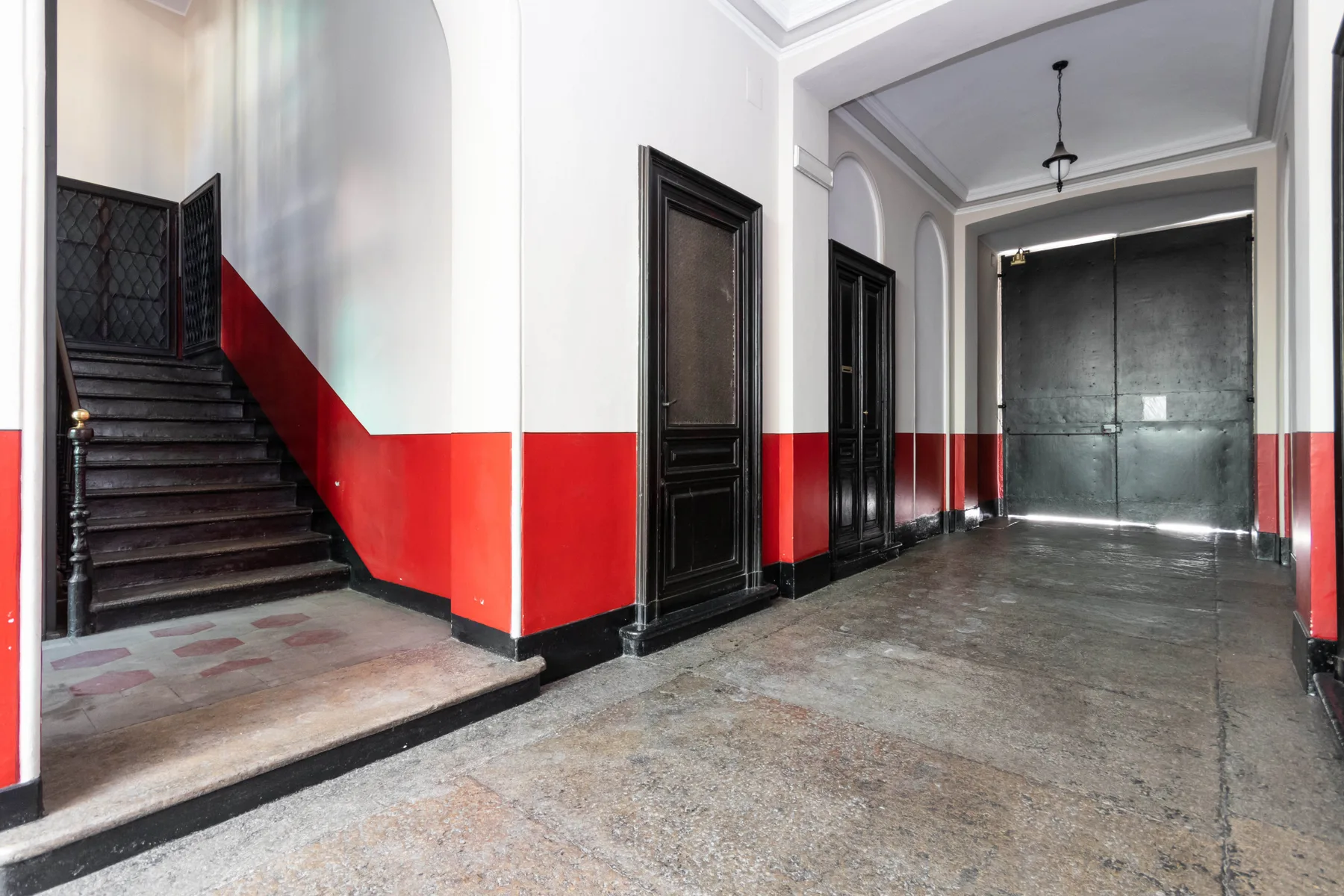 An interior entrance hall with a staircase and large dark double doors.