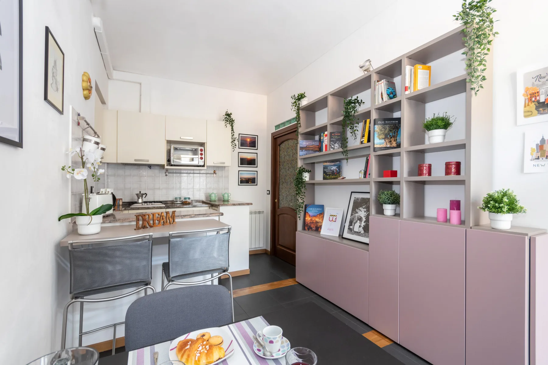 A bright kitchen and dining area with a long open shelving unit along one wall.