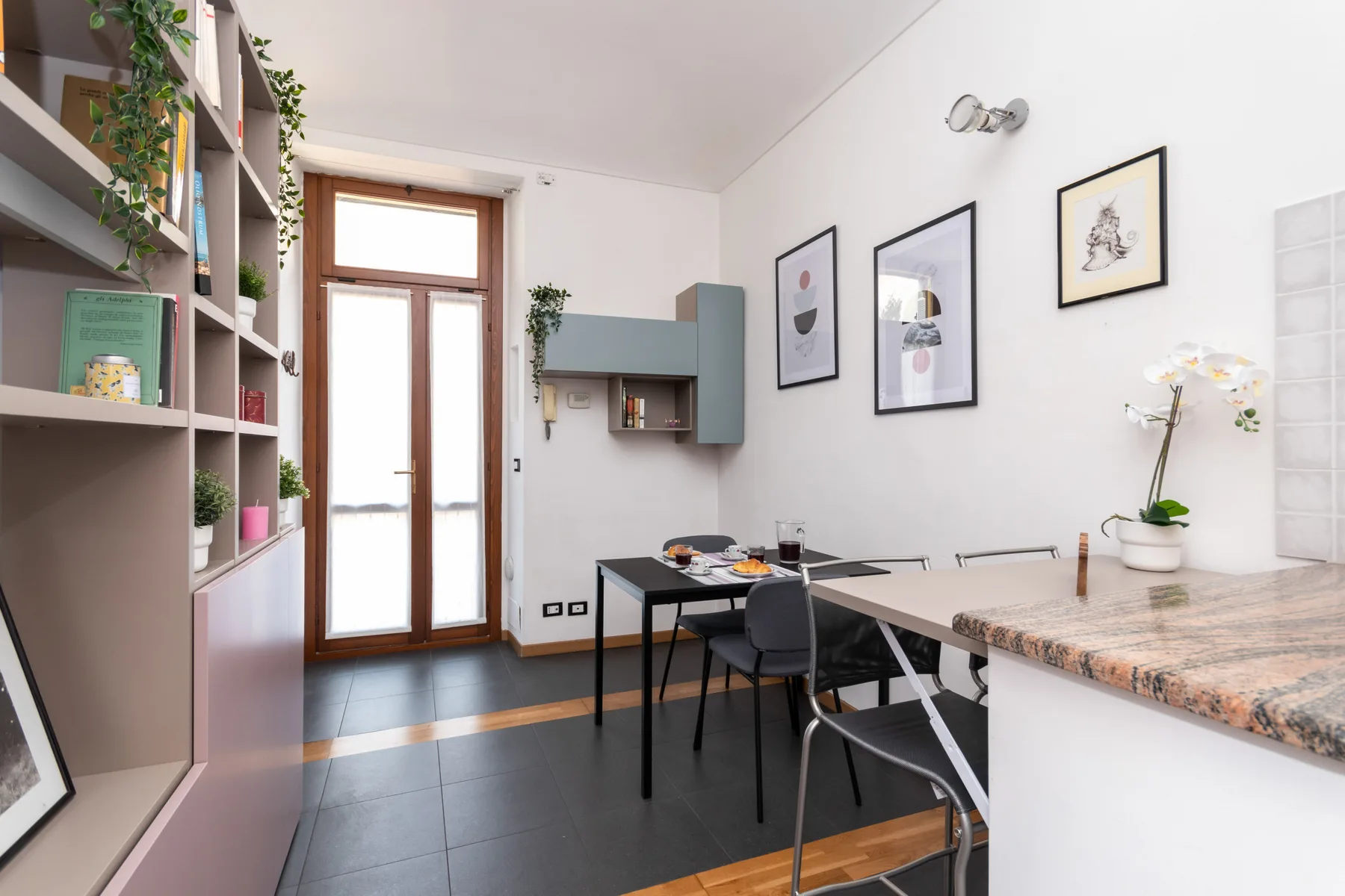 A bright dining area with a table, seating, and built-in shelving.