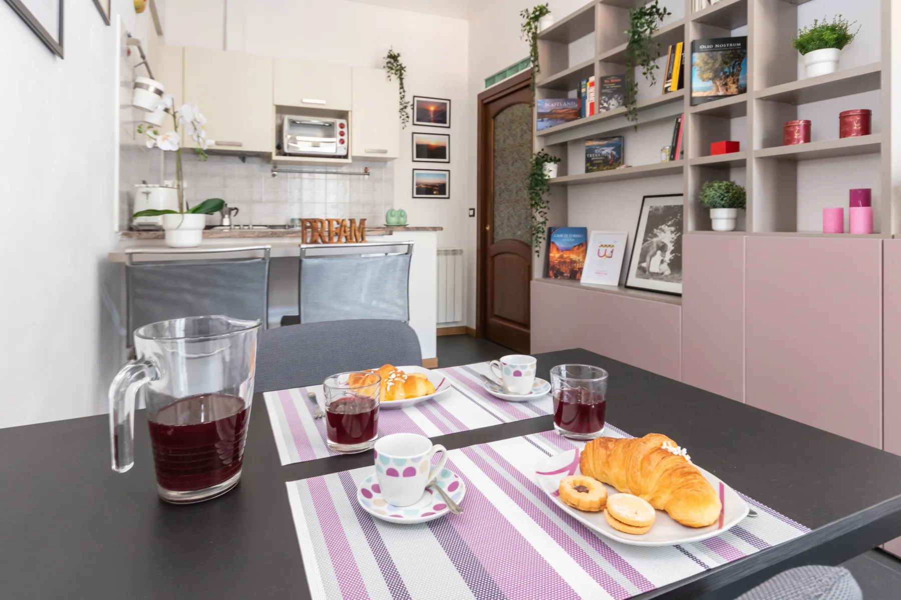 A dining table is set with striped placemats, drinks, and pastries.