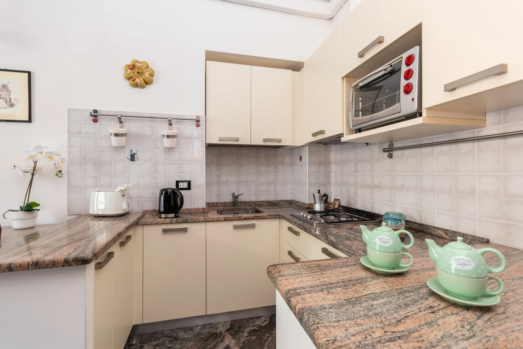 A kitchen with cream cabinetry, granite countertops, and a built-in microwave.