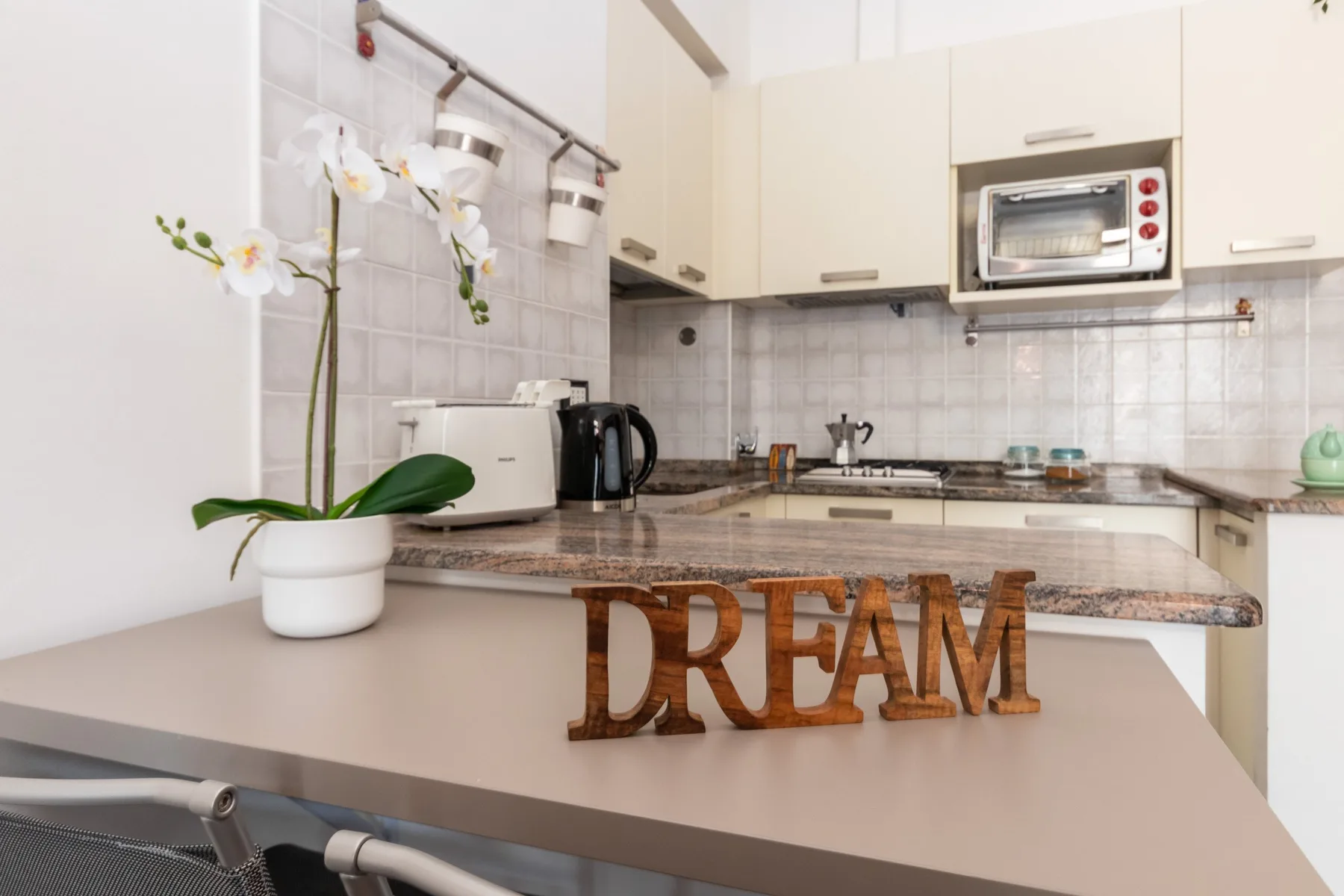 A bright kitchen with pale cabinets and a countertop holding small appliances.