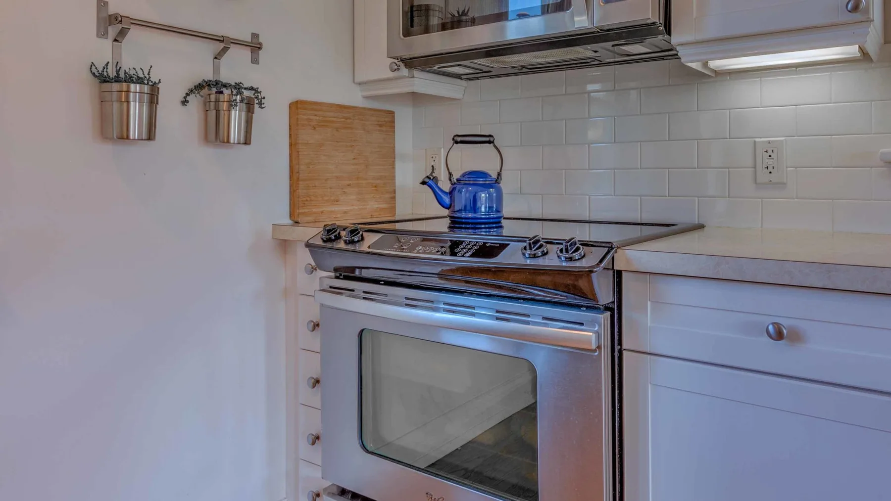A kitchen with a stainless-steel stove and a blue kettle on the cooktop.