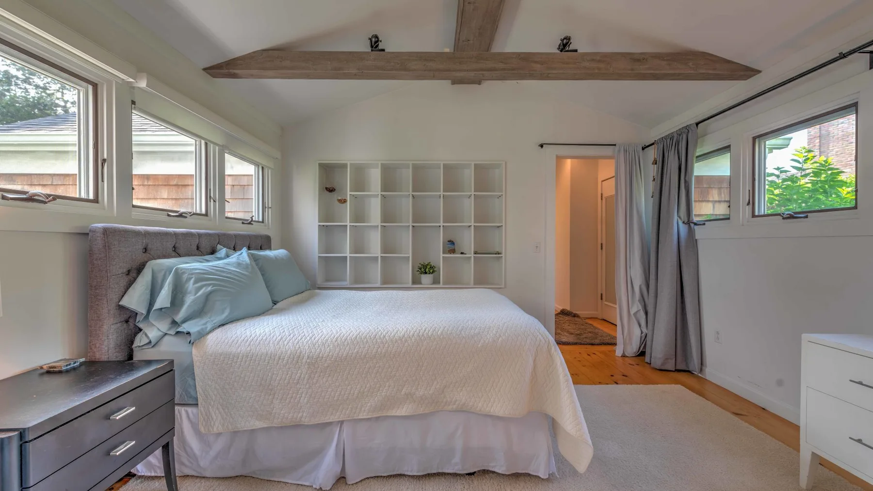 A bedroom with a neatly made bed and built-in shelving.