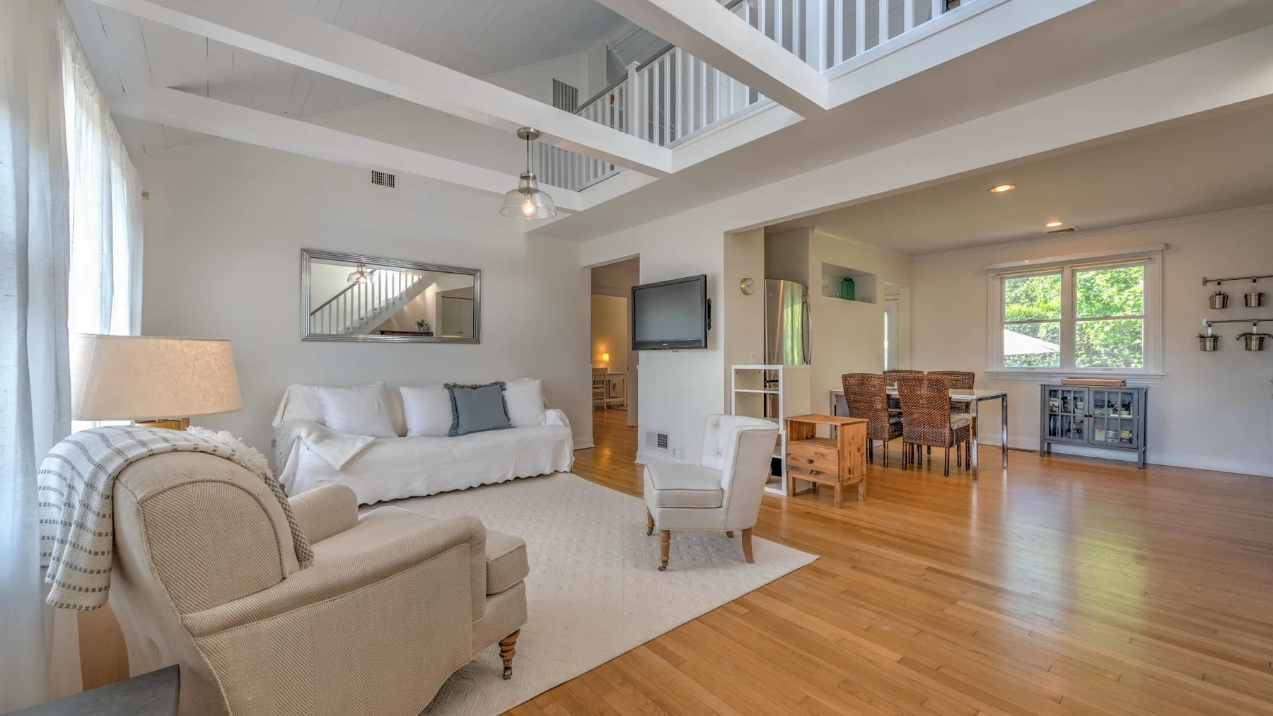 A bright open-plan living and dining area with seating and a wooden table.