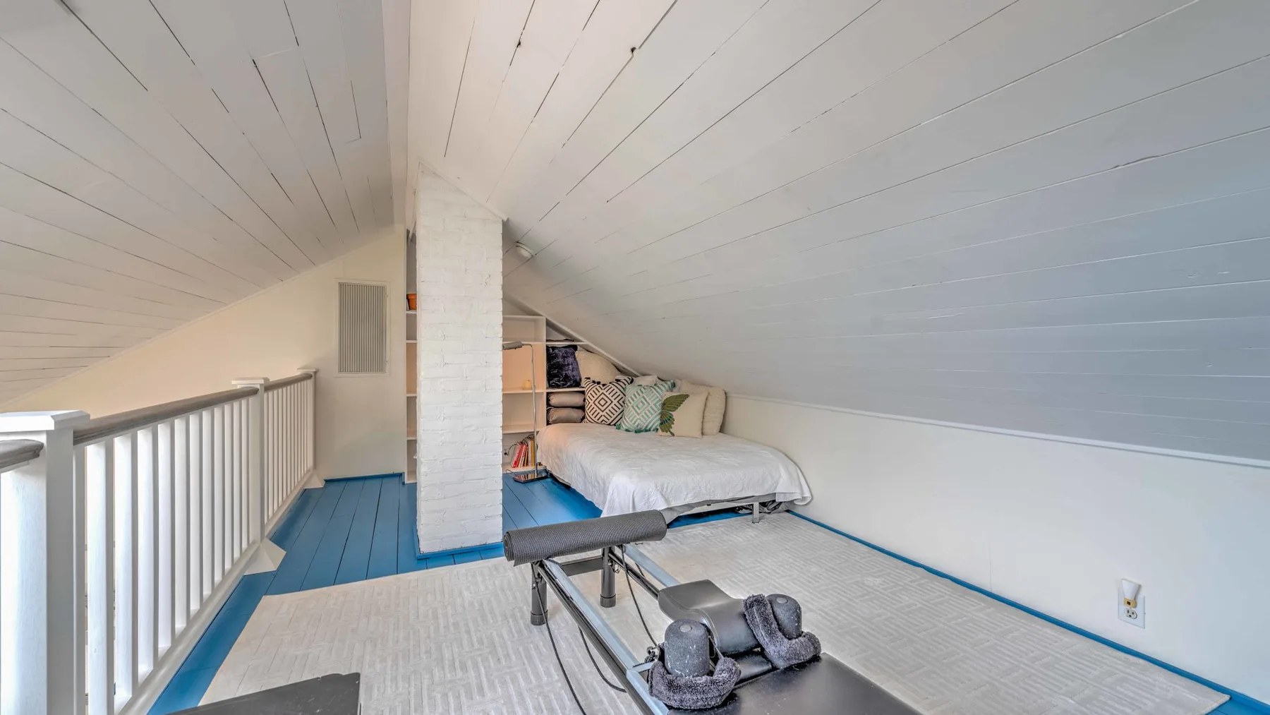 A sloped-ceiling bedroom with a bed and a blue floor.