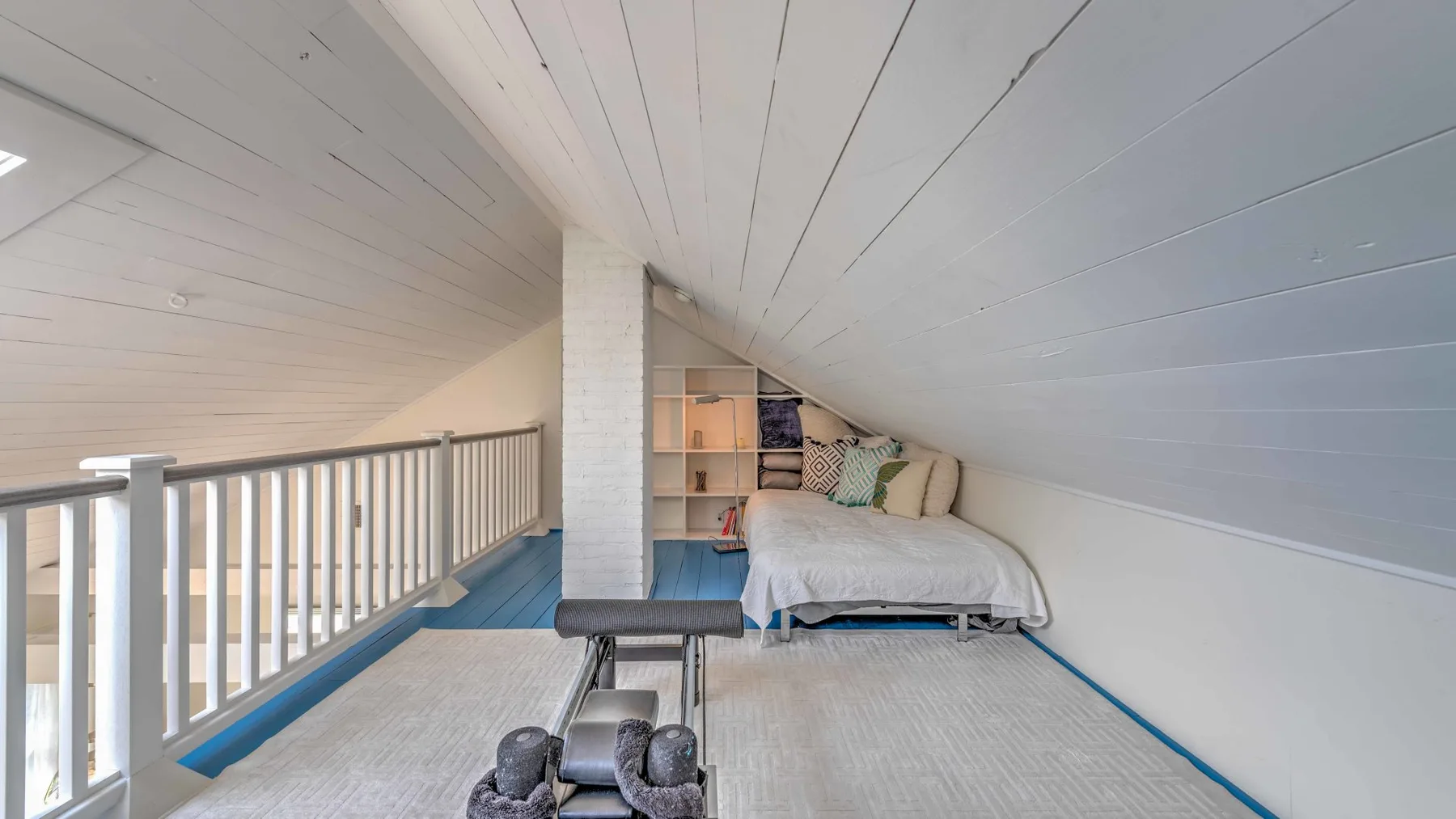 A loft sleeping area with a bed beneath a sloped ceiling.