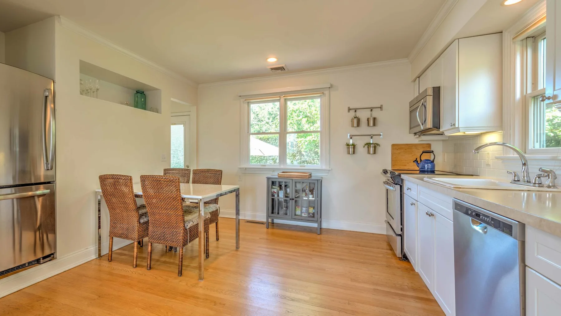A bright kitchen and dining area with wooden flooring and a central window.