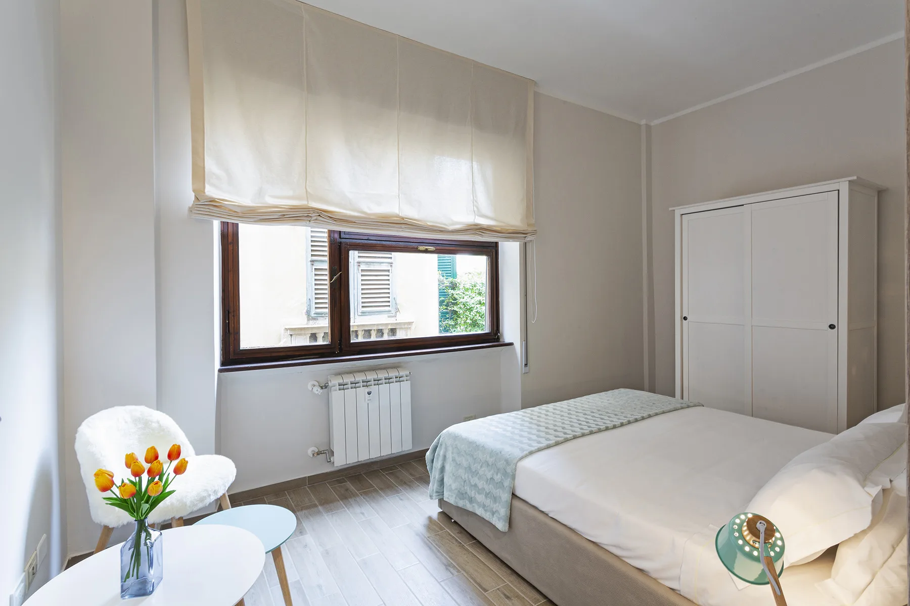 A bright bedroom with a bed, a single bed, and a window with a raised blind.