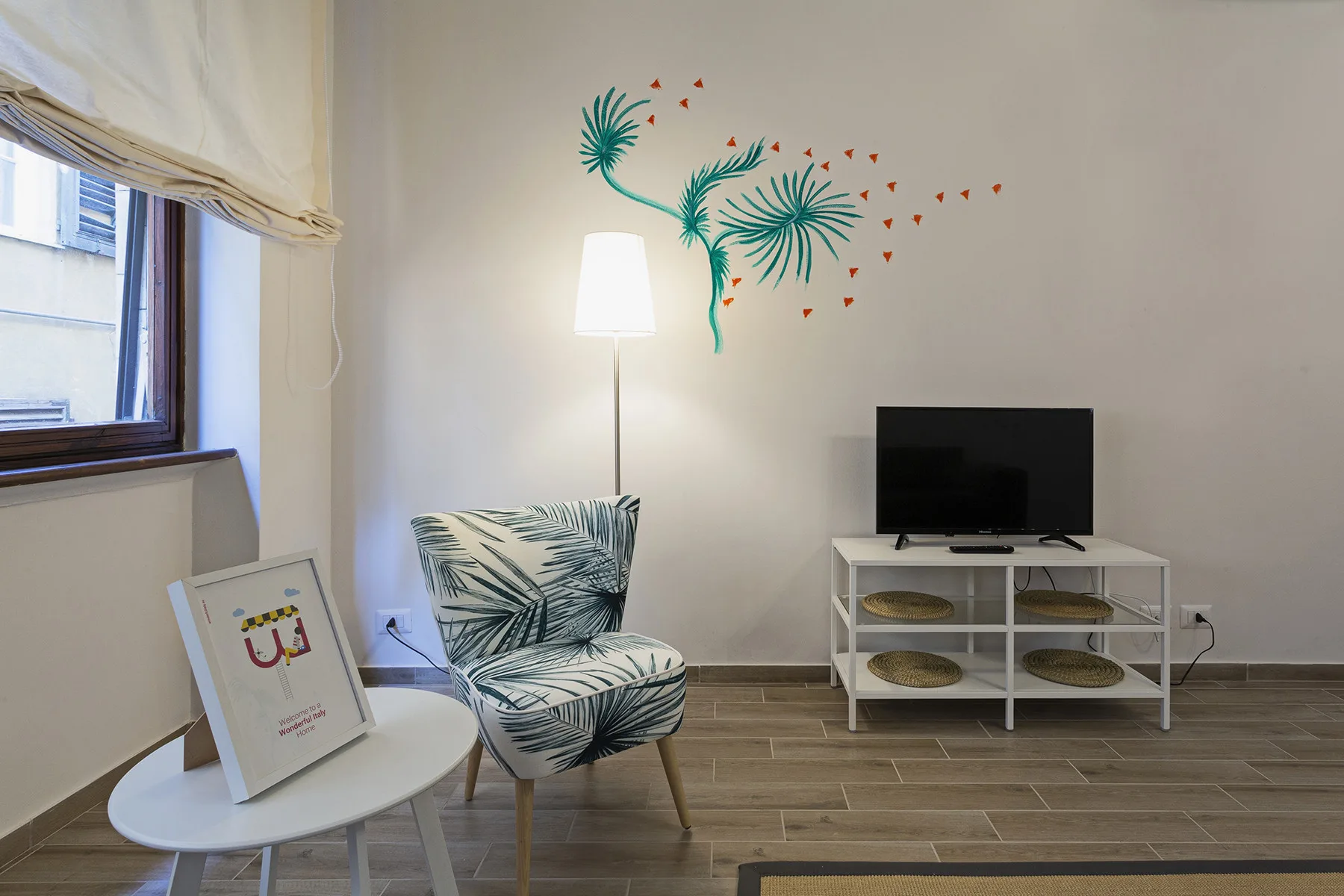 A sitting area with a television, patterned seating, and a floor lamp.